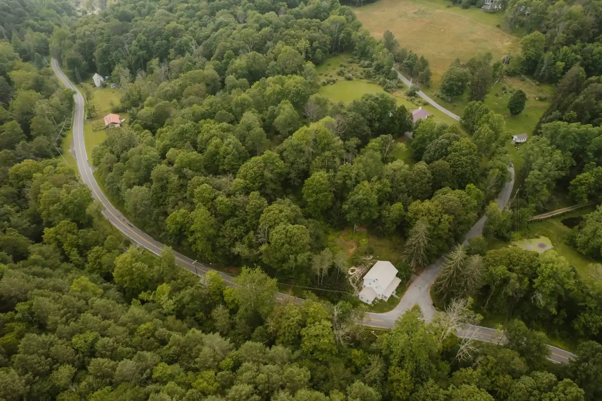 Aerial view of a winding road through wooded hills
